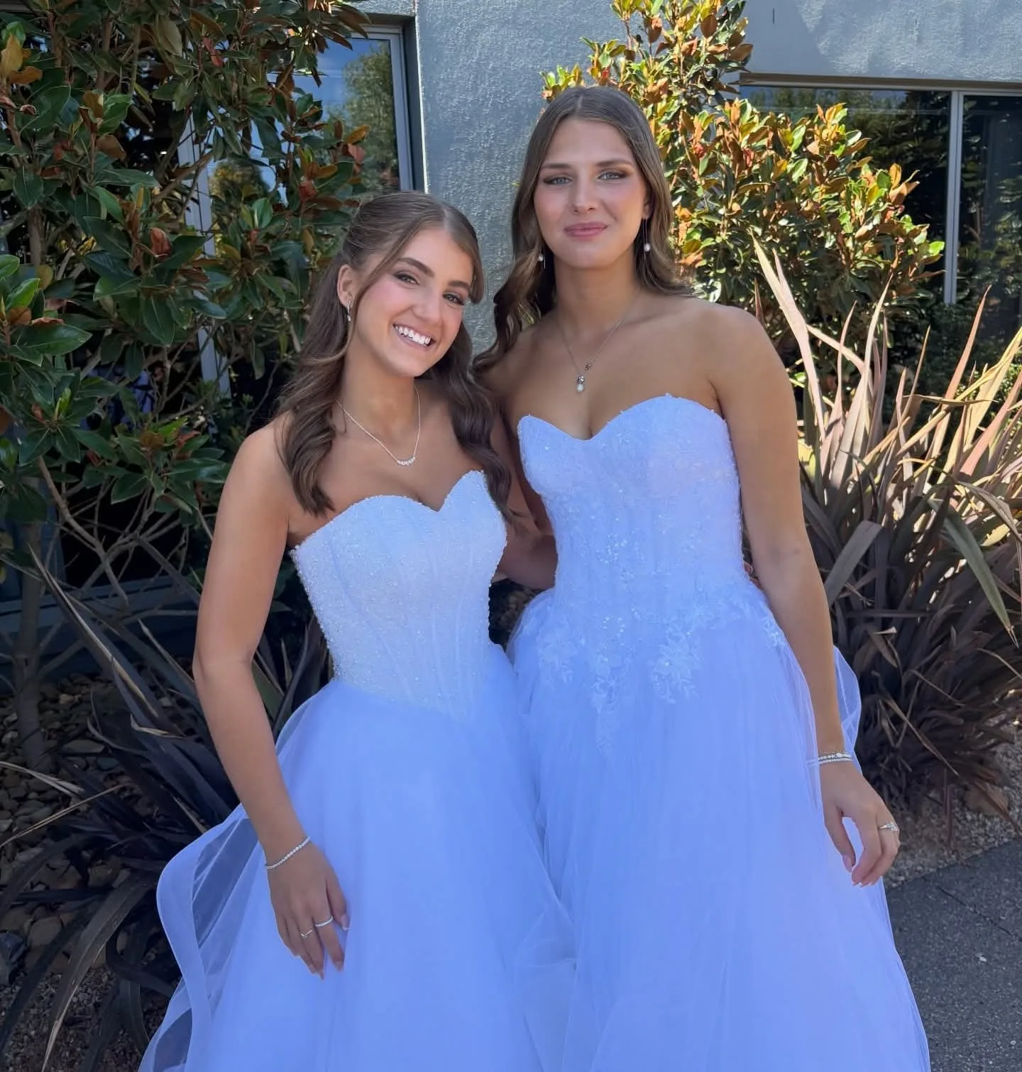 Two young women in white gowns, even tans