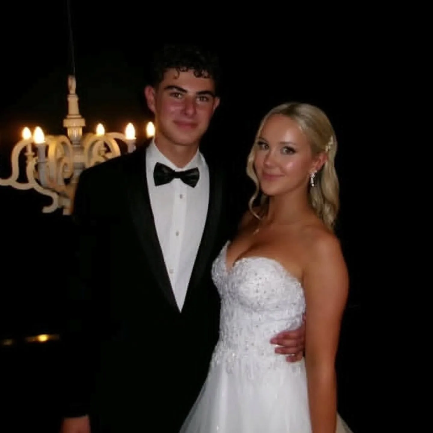 Couple at night, tanned blonde woman in a white gown