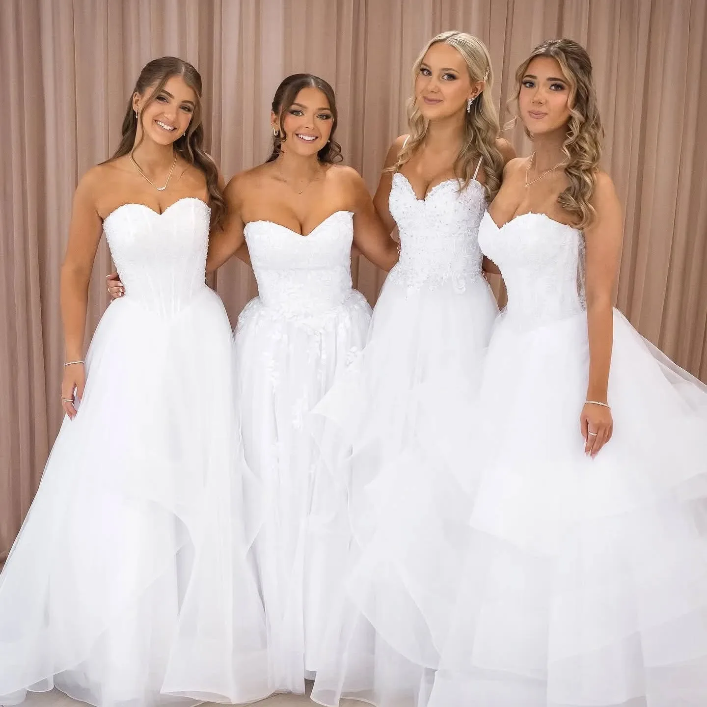 Four debutantes in white gowns, matched bronze glow