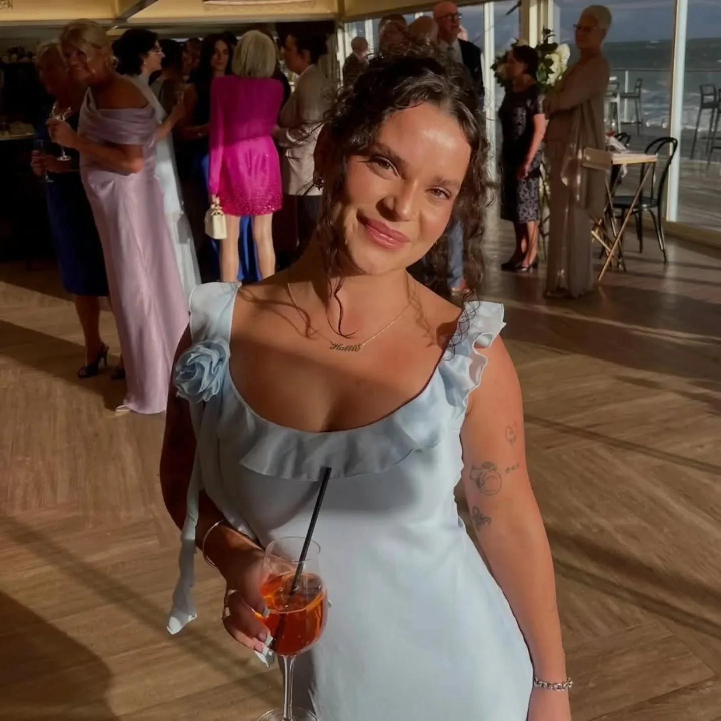Tanned woman in blue dress at a beachfront event